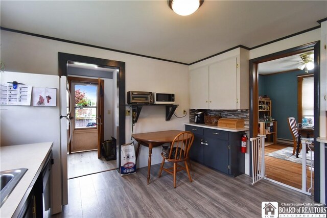 kitchen with light countertops, dark wood-style floors, white appliances, backsplash, and a baseboard heating unit
