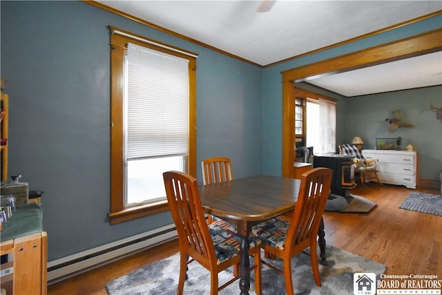 dining room with a baseboard radiator, ornamental molding, and wood finished floors