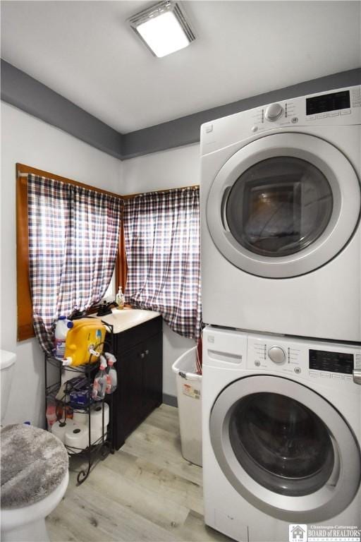 washroom featuring stacked washing machine and dryer and light wood-style floors
