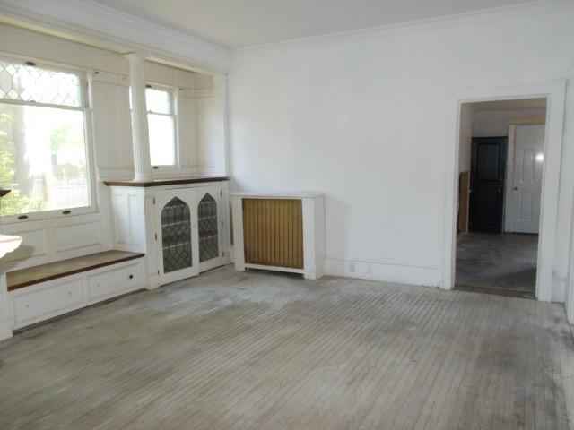 unfurnished living room featuring crown molding and light wood-type flooring