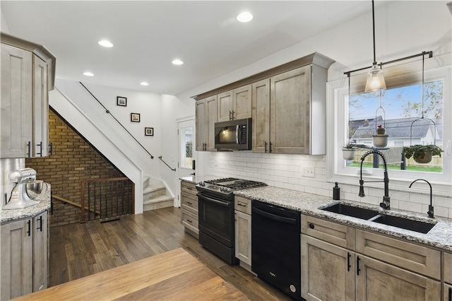 kitchen featuring dishwasher, gas stove, stainless steel microwave, a sink, and light stone countertops
