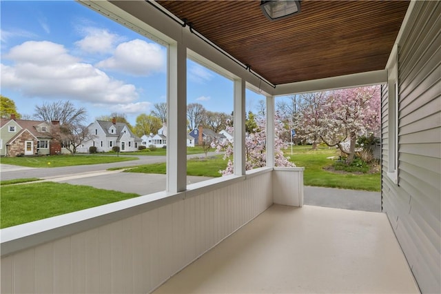 unfurnished sunroom featuring a residential view, wood ceiling, and finished concrete flooring