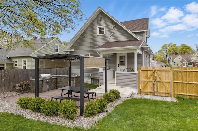 back of house with roof with shingles, exterior kitchen, a pergola, a gate, and a patio area