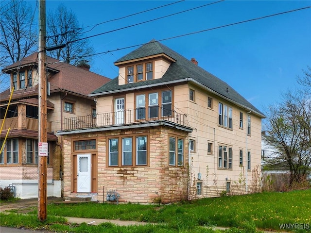 329 Jewett Ave, Buffalo, NY 14214 - view of front facade featuring stone siding, a front lawn, a balcony, a chimney, and roof with shingles