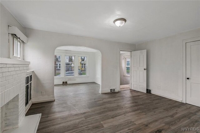 329 Jewett Ave, Buffalo, NY 14214 - unfurnished living room with a fireplace, arched walkways, dark wood-style floors, and baseboards