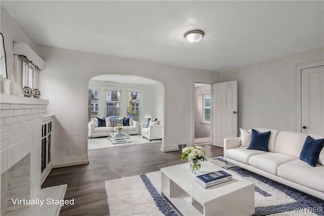 329 Jewett Ave, Buffalo, NY 14214 - living room featuring arched walkways, a brick fireplace, dark wood-type flooring, and baseboards
