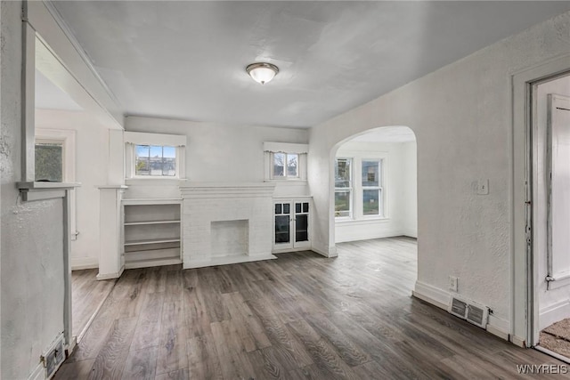 329 Jewett Ave, Buffalo, NY 14214 - unfurnished living room with arched walkways, wood finished floors, a fireplace, and baseboards