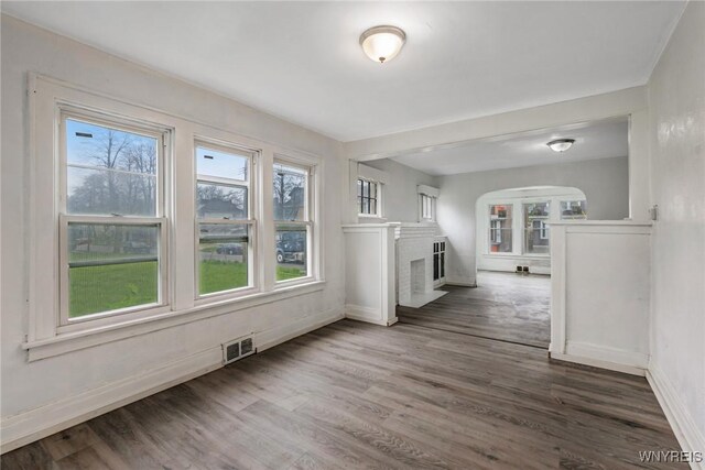 329 Jewett Ave, Buffalo, NY 14214 - unfurnished living room with a brick fireplace, arched walkways, wood finished floors, and baseboards