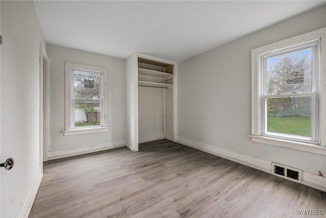 329 Jewett Ave, Buffalo, NY 14214 - unfurnished bedroom with multiple windows, wood finished floors, baseboards, and a closet