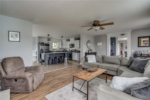 29441 Beaver Meadow Mews, Lyme, NY 13622 - living area featuring a ceiling fan, light wood finished floors, and decorative columns