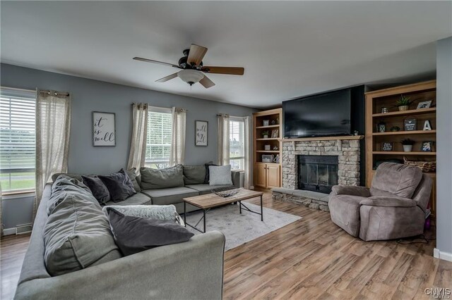 29441 Beaver Meadow Mews, Lyme, NY 13622 - living area with a ceiling fan, a stone fireplace, light wood-style floors, and baseboards