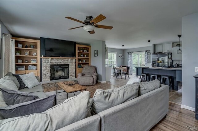 29441 Beaver Meadow Mews, Lyme, NY 13622 - living room featuring ceiling fan, a stone fireplace, baseboards, and light wood finished floors