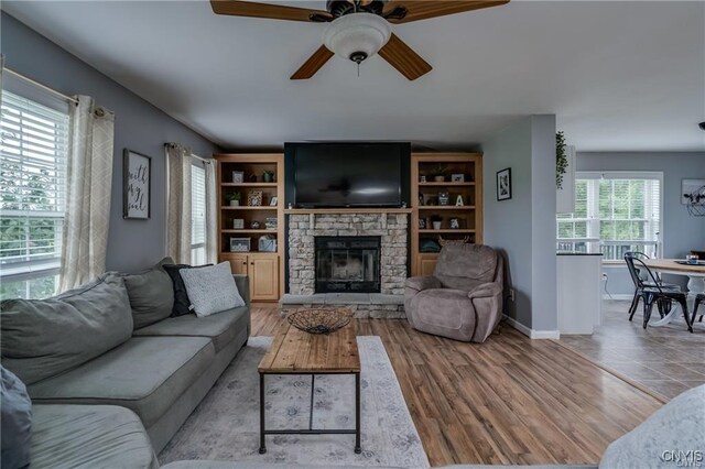 29441 Beaver Meadow Mews, Lyme, NY 13622 - living area with a stone fireplace, a ceiling fan, baseboards, and wood finished floors