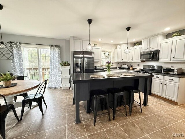 29441 Beaver Meadow Mews, Lyme, NY 13622 - kitchen with appliances with stainless steel finishes, dark countertops, decorative backsplash, a kitchen island, and white cabinets