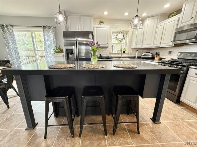 29441 Beaver Meadow Mews, Lyme, NY 13622 - kitchen featuring appliances with stainless steel finishes, a breakfast bar area, a kitchen island, decorative backsplash, and white cabinetry