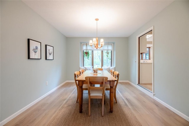 dining room featuring light wood-type flooring, a chandelier, and baseboards