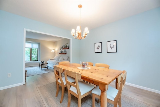 dining space featuring light wood-style floors, a chandelier, and baseboards