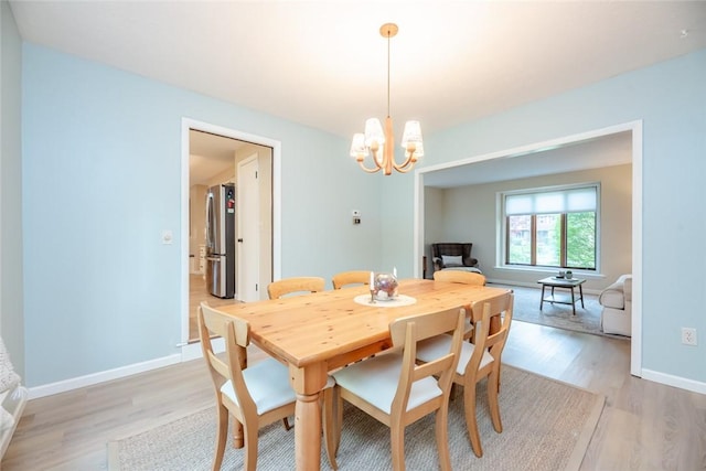 dining area with light wood-type flooring, a chandelier, and baseboards