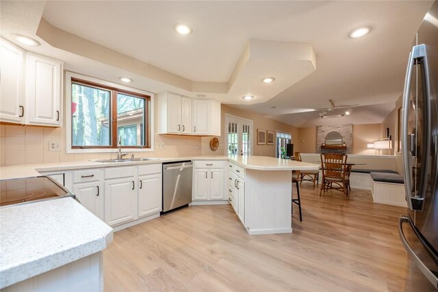 kitchen featuring stainless steel appliances, a peninsula, a sink, plenty of natural light, and recessed lighting