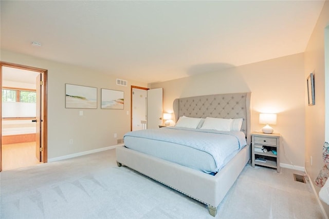 bedroom with light carpet, baseboards, and ensuite bath