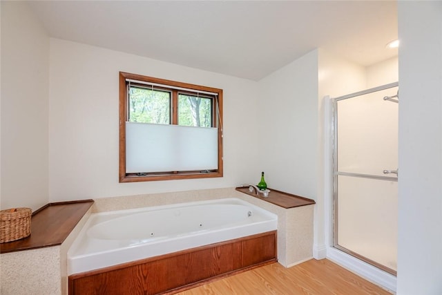 full bath featuring a shower stall, a jetted tub, and wood finished floors