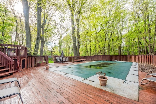 view of swimming pool featuring a wooden deck, a fenced backyard, and a diving board