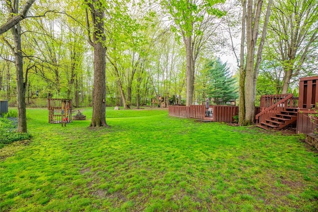 view of grassy yard with a deck and stairs