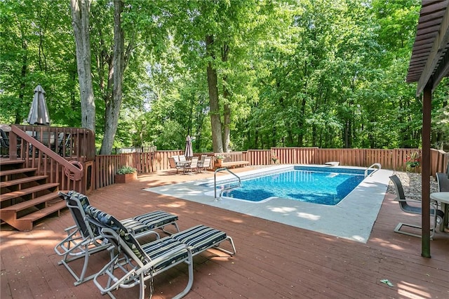 view of swimming pool featuring outdoor dining space, a wooden deck, and a fenced backyard