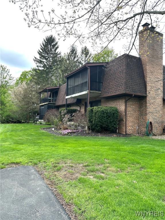 view of home's exterior featuring roof with shingles, a yard, and brick siding
