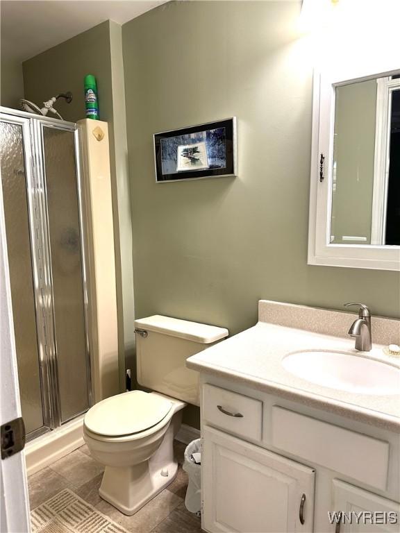 bathroom featuring a shower stall, toilet, and vanity