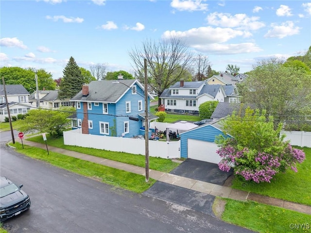 view of front of house featuring a residential view, a garage, a chimney, and an outdoor structure