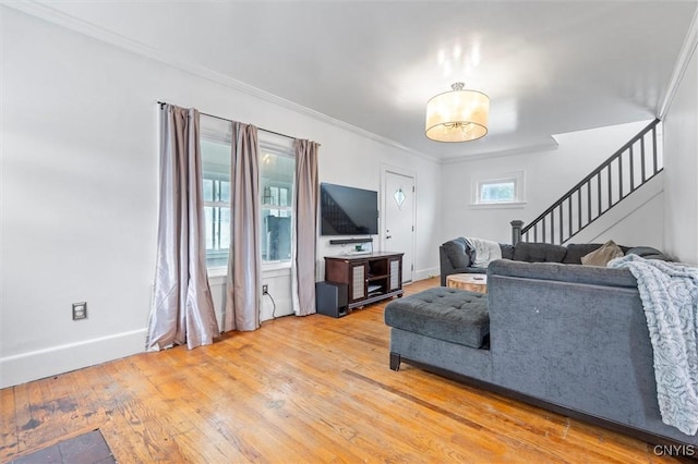 living area with stairs, light wood finished floors, baseboards, and ornamental molding