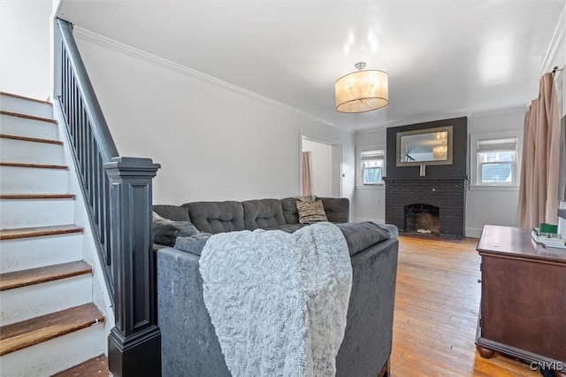 living room featuring stairway, ornamental molding, light wood-style floors, and a fireplace