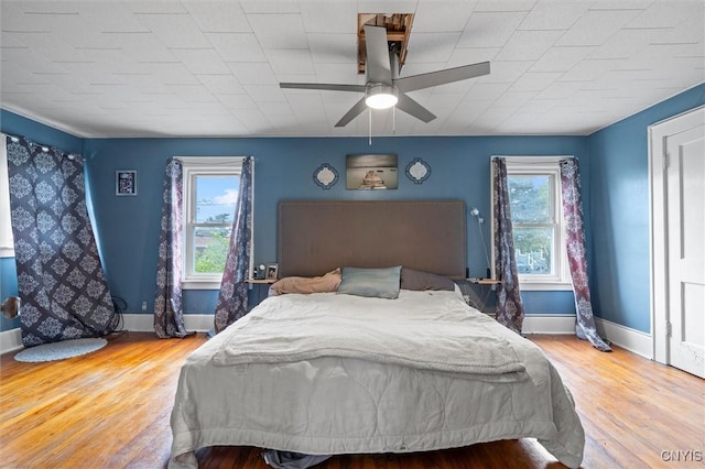 bedroom featuring baseboards, wood finished floors, and ceiling fan