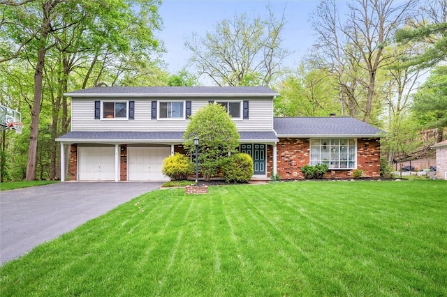 traditional home with asphalt driveway, an attached garage, a front yard, and brick siding