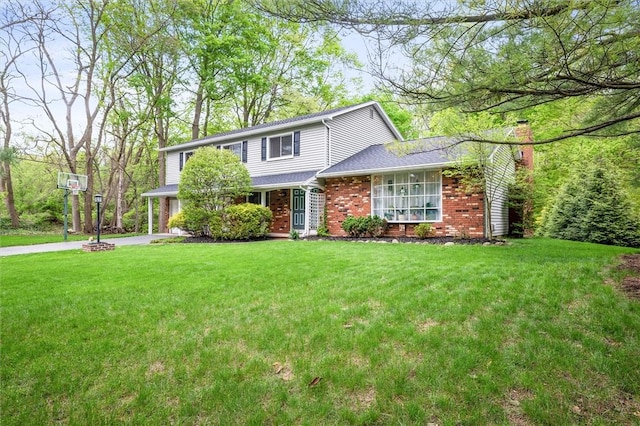 traditional-style home featuring a front yard, brick siding, a chimney, and concrete driveway