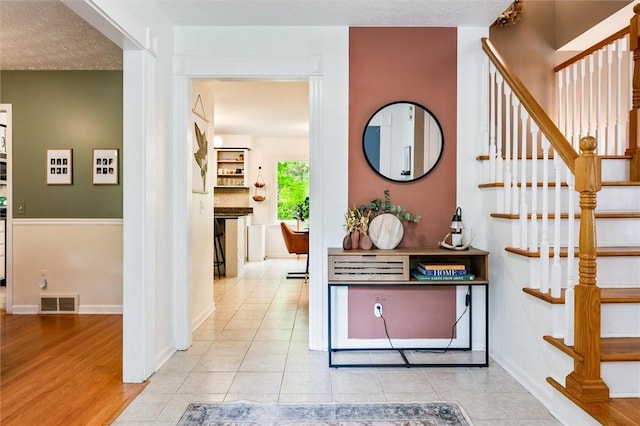 entryway with stairs, tile patterned flooring, and baseboards