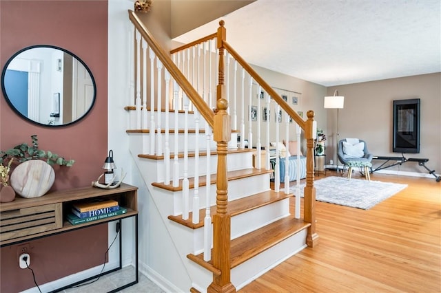 stairway with wood finished floors and baseboards