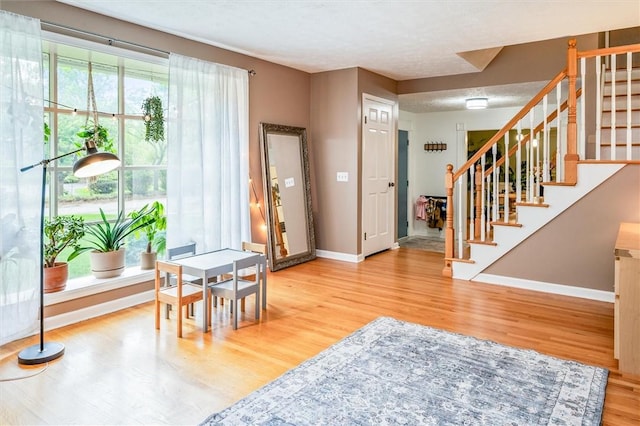 entryway with wood finished floors, baseboards, stairs, and a textured ceiling
