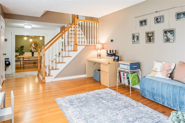 living room with stairway, wood finished floors, and baseboards