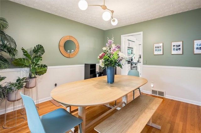 dining space featuring a textured ceiling, wood finished floors, and baseboards