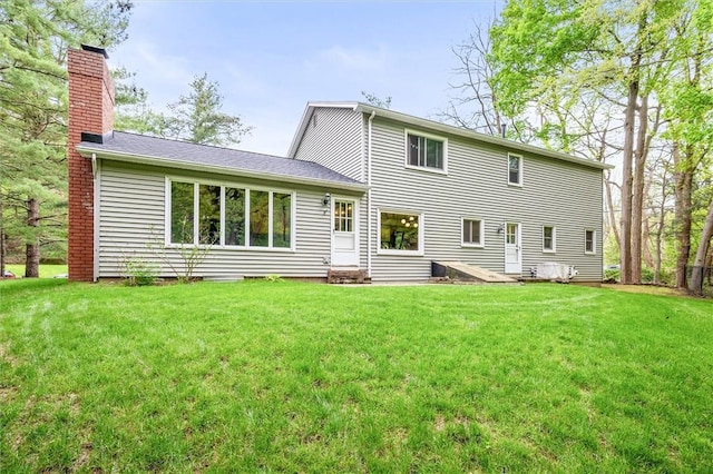 back of property featuring a chimney, a lawn, and entry steps