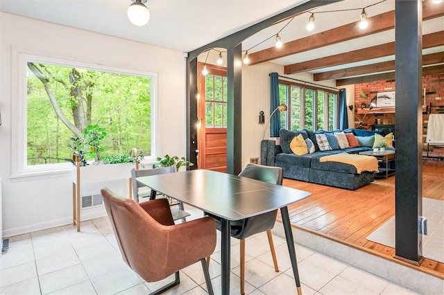 dining room with light tile patterned floors, baseboards, arched walkways, and beamed ceiling