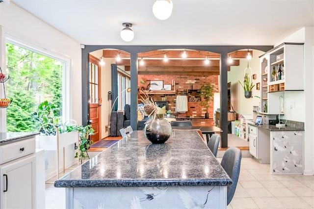 dining space with arched walkways, brick wall, and light tile patterned floors