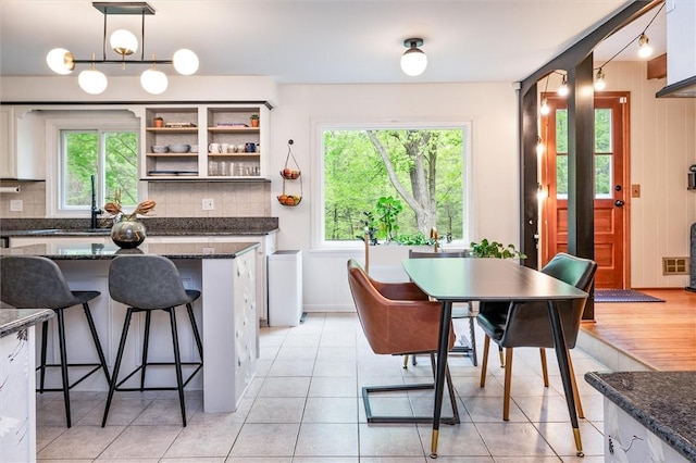 kitchen featuring a sink, backsplash, a kitchen bar, and hanging light fixtures