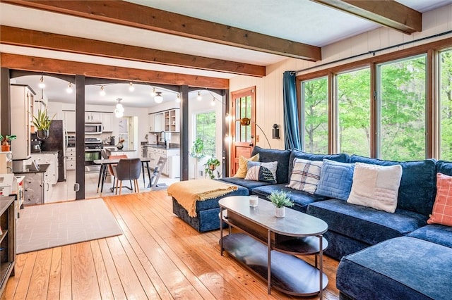 living area with light wood-type flooring, plenty of natural light, and beam ceiling