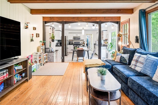 living room with beam ceiling, light wood-style floors, and wooden walls