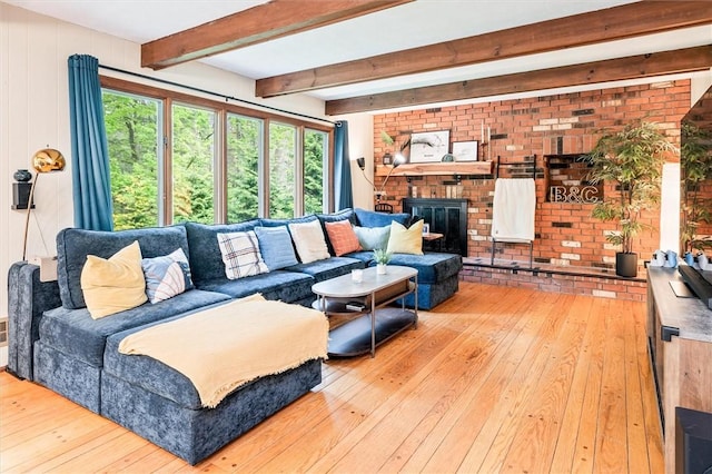 living area featuring hardwood / wood-style flooring, plenty of natural light, beam ceiling, and a brick fireplace