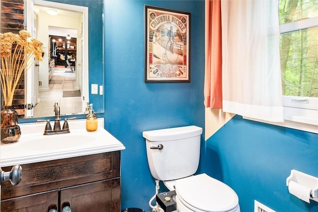 bathroom with toilet, healthy amount of natural light, and vanity