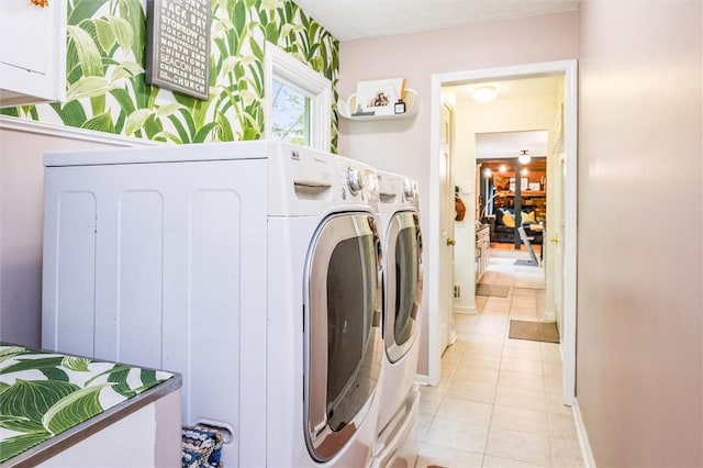 laundry room with washing machine and dryer, light tile patterned floors, and baseboards